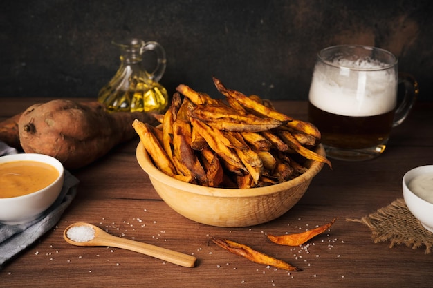 Foto deliciosas y saludables patatas fritas caseras hechas en una freidora de aire con salsas y taza de cerveza sobre un fondo rústico oscuro