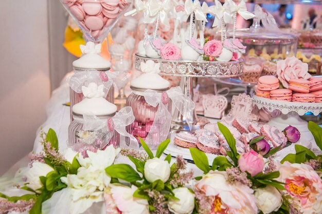 Deliciosas sobremesas na barra de chocolate do casamento na área do buffet: biscoitos cobertos com glacê, decorados com anjos, camafeu, botões de rosa açucarados e tintura de prata