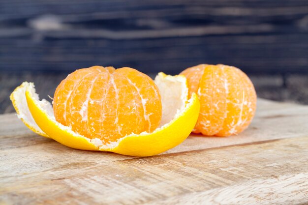 Deliciosas tangerinas, casca de laranja descascada sobre uma mesa de madeira, frutas cítricas saudáveis com muitas vitaminas