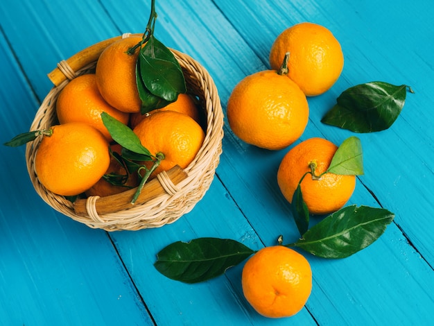 Deliciosas tangerinas maduras brilhantes com folhas em uma mesa de madeira