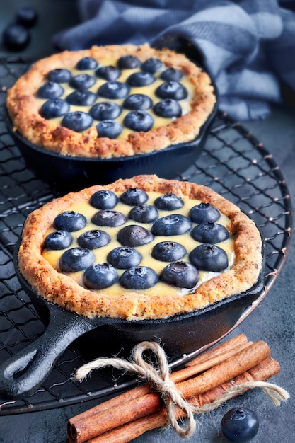 Deliciosas tartaletas de arándanos con crema de vainilla sobre madera rústica gris