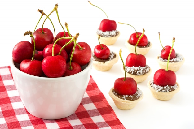 Deliciosas tartaletas de chocolate con una cereza y coco aislado