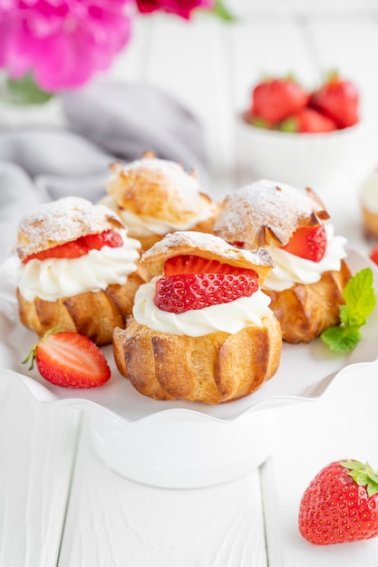 Deliciosas tartas caseras de hojaldre Profiterole con natillas de fresa y glaseado en polvo