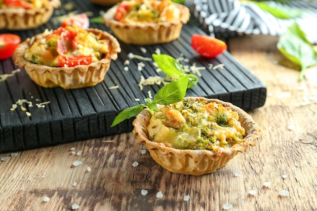 Deliciosas tartas crujientes con brócoli sobre mesa de madera