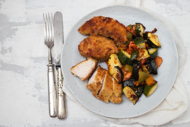 Deliciosas tiras de pechuga de pollo empanadas fritas crujientes con verduras al horno