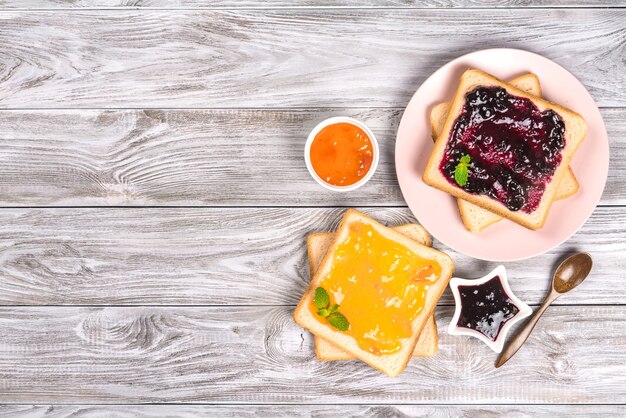 Deliciosas torradas com várias geléias doces em fundo cinza. Copyspace para seu texto, banner.