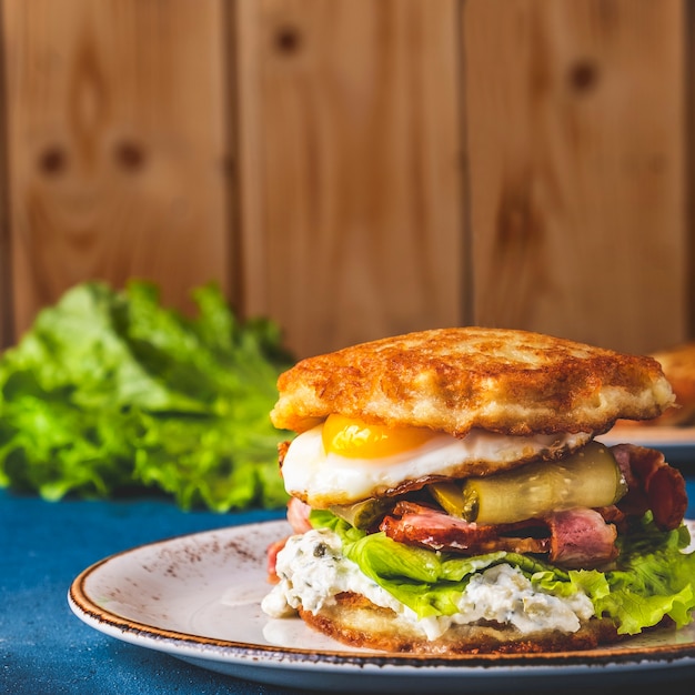 Deliciosas tortitas de patata hamburguesa huevos fritos, tocino y pepino salado.