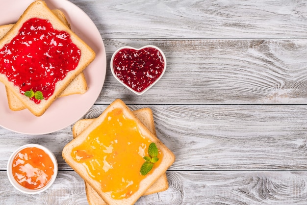 Deliciosas tostadas con diversas mermeladas dulces sobre fondo gris. Copyspace para su texto, banner.