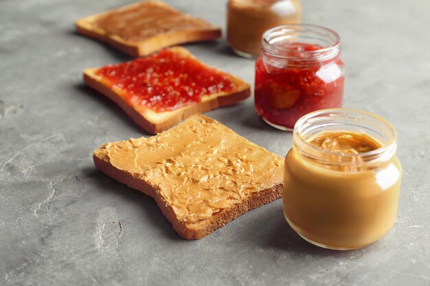 Deliciosas tostadas con mantequilla de maní y mermelada sobre fondo gris