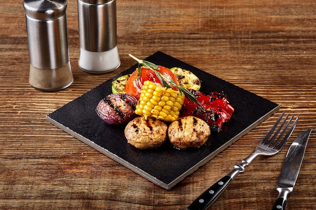 Deliciosas verduras a la parrilla Tomates pimiento rojo cebolla calabacín maíz y champiñones decorados con romero vista de cerca