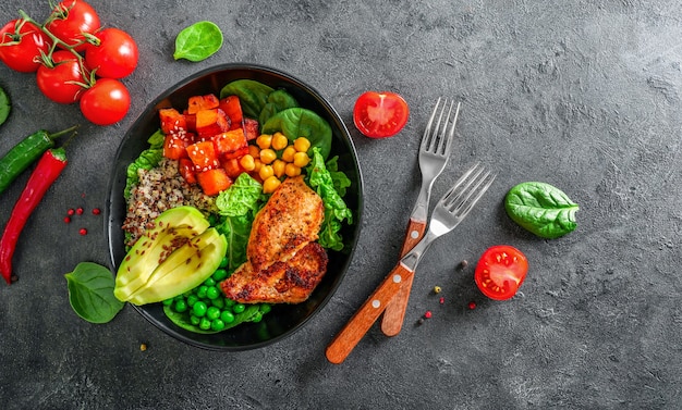 Delicioso almuerzo con quinua, aguacate, papa dulce, pollo frito y condimentos sobre fondo oscuro. Vista superior.