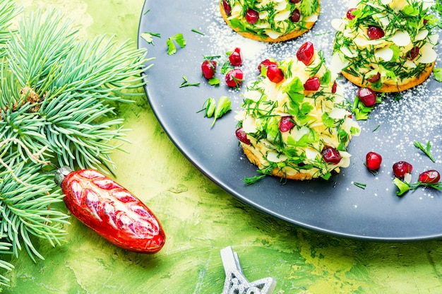 Delicioso aperitivo para a mesa de Natal. Canapés com queijo, alho e romã.