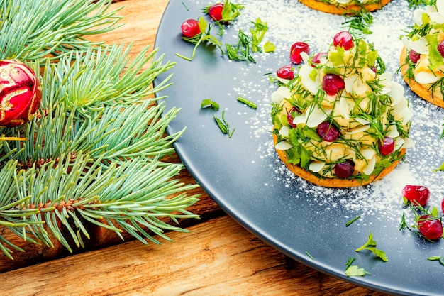 Delicioso aperitivo para a mesa de Natal. Canapés com queijo, alho e romã.