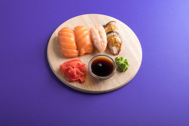 Delicioso y apetitoso sushi nigiri servido en platos de madera con salsa de soja. Mesa morada
