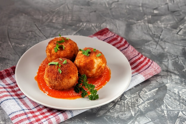 Delicioso arancini italiano quente - bolinhos de arroz recheados com queijo em molho de tomate, em um prato sobre uma velha mesa de madeira