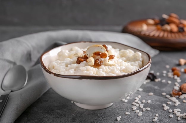 Delicioso arroz con leche con nueces y pasas en un tazón sobre la mesa gris