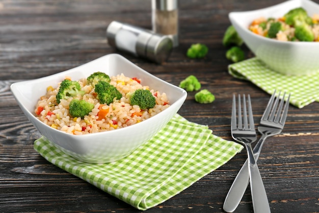 Delicioso arroz pilaf con brócoli en un tazón sobre mesa de madera