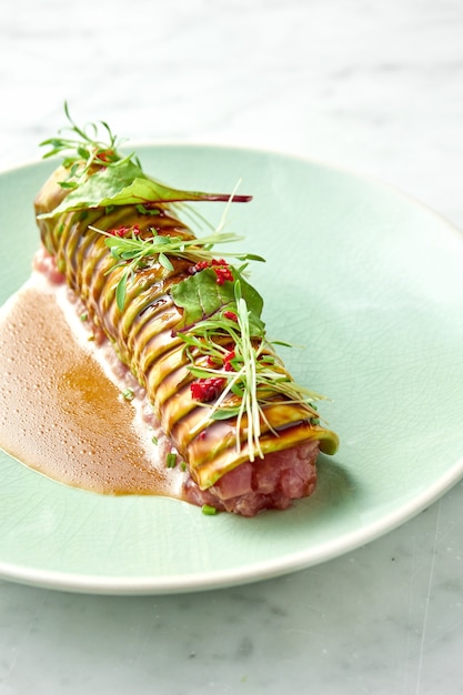 Delicioso atum tártaro com abacate, coentro, servido em croutons de centeio em um prato branco com ovo escalfado. lanche da culinária japonesa