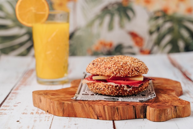 Delicioso bagel com pão de gergelim e chia, dentro contém tomate, presunto e frango em tiras.