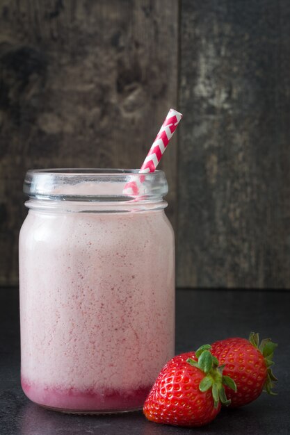 Delicioso batido de fresa en frasco en la mesa de madera