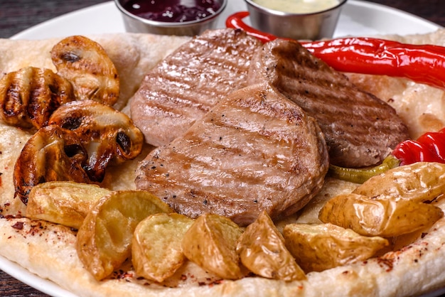 Foto delicioso bife de frango suculento com batatas assadas, cogumelos e molhos em um prato branco