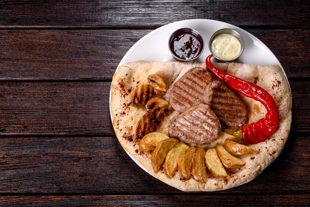 Delicioso bistec de pollo jugoso con papas al horno, champiñones y salsas en un plato blanco