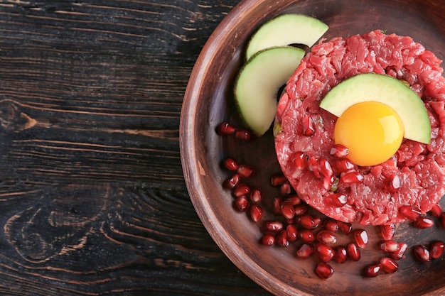 Delicioso bistec tartar con yema de aguacate y semillas de granada en plato