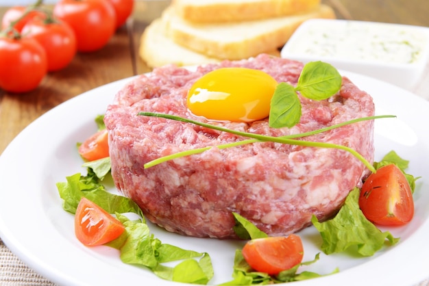 Delicioso bistec tartar con yema de huevo en un plato en el primer plano de la mesa