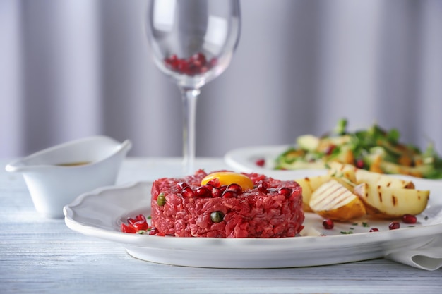 Delicioso bistec tartar con yema y semillas de granada en plato