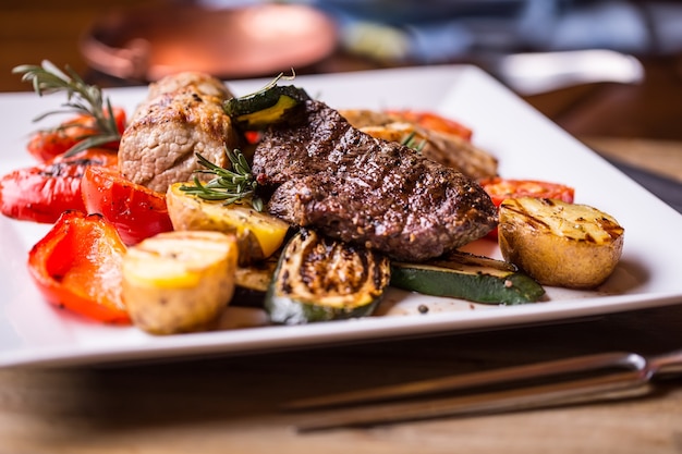 Delicioso bistec de ternera jugosa en un plato con patatas y verduras a la parrilla.