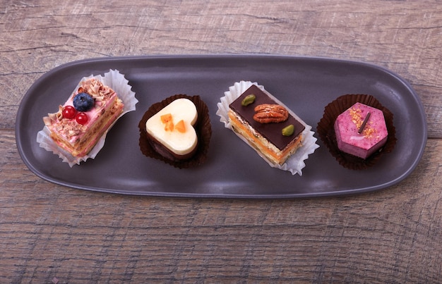 Delicioso bizcocho para el día de San Valentín. La cinta roja está forrada en forma de corazón sobre una mesa de madera oscura. Antecedentes del día de San Valentín, lugar de mesa. Concepto del día de la boda de la madre, de la mujer.