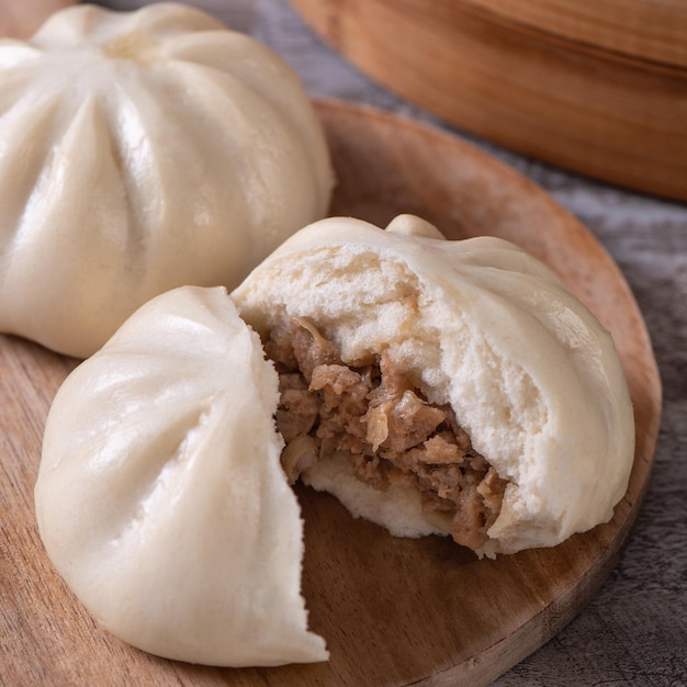 Delicioso bollo de carne al vapor chino baozi está listo para comer en un plato para servir y un vaporizador de cerca el concepto de diseño de producto de espacio de copia