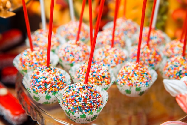 Delicioso bolo aparece, polvilhado com bolas coloridas, deite-se em um suporte de vidro.