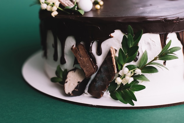 Delicioso bolo de chocolate caseiro com doces sobre fundo verde, close-up