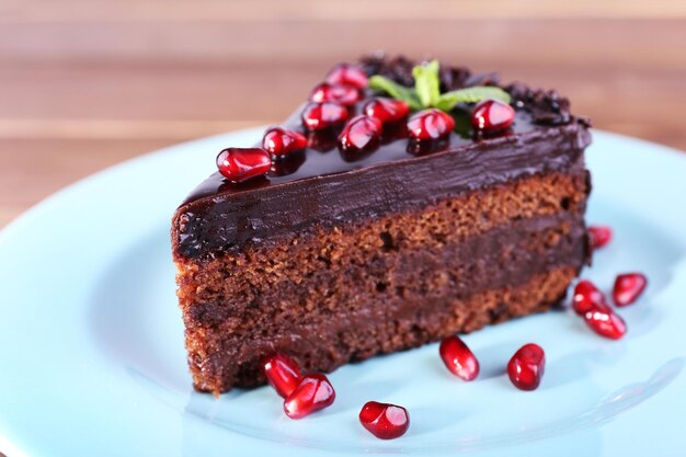 Delicioso bolo de chocolate decorado com sementes de romã no prato na mesa