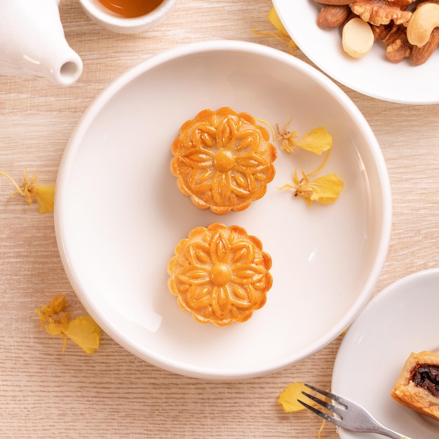 Delicioso bolo de lua para o festival MidAutumn com belo padrão decorado com flores amarelas e chá Conceito de design de pastelaria festiva da tarde