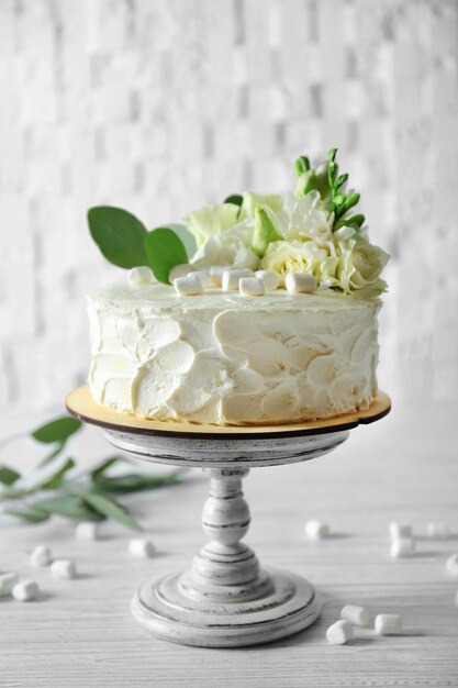 Foto delicioso bolo decorado com marshmallows e flores na mesa de madeira