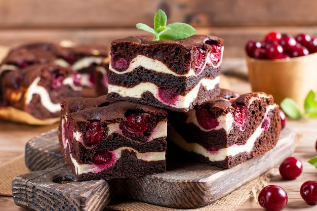 Foto delicioso brownie de chocolate con cerezas trozos de pastel sobre mesa de madera