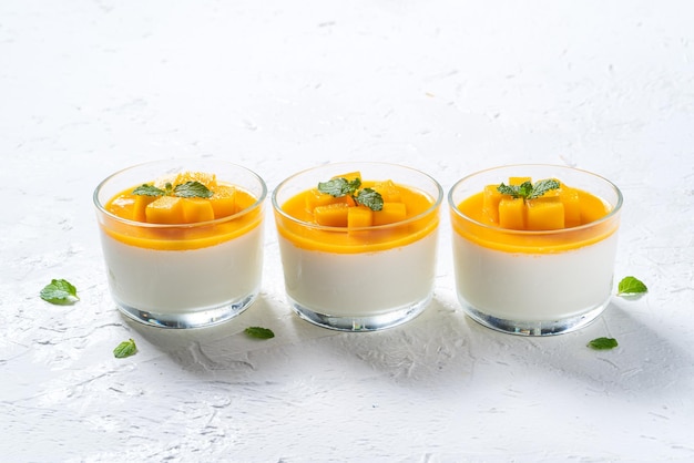 Delicioso budín de mousse de panna cotta de mango de doble color sobre fondo blanco de mesa