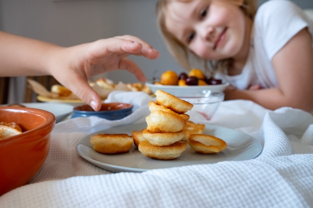 Delicioso café da manhã com mini panquecas, cerejas, damascos e geleia em uma mesa branca