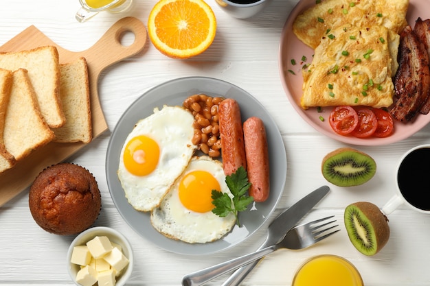 Delicioso café da manhã ou almoço com ovos fritos na superfície de madeira branca, vista superior