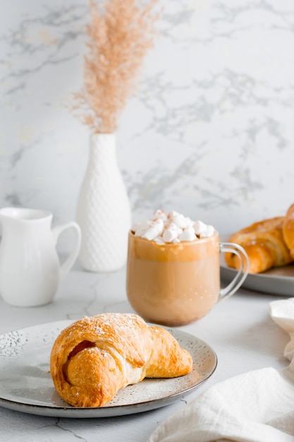 Delicioso café con malvaviscos y croissants en platos sobre la mesa Estilo de vida refrigerio casero Vista vertical