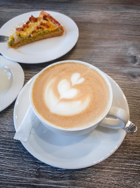 Delicioso cappuccino perfumado com um padrão na superfície da espuma em uma xícara de porcelana branca Café refrescante no café da manhã