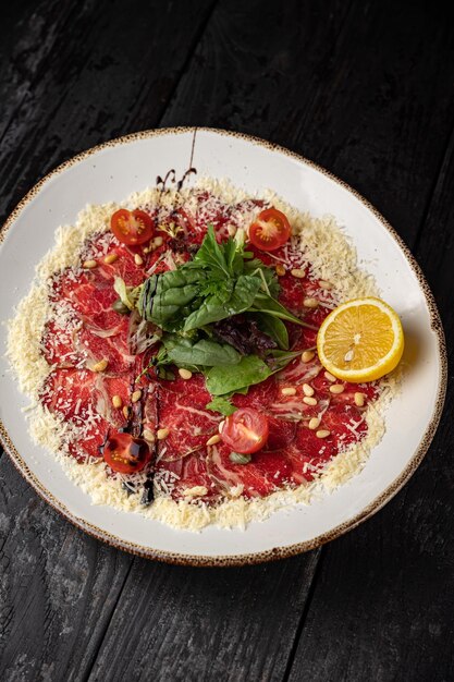 delicioso carpaccio de ternera en un plato sobre una mesa de madera oscura