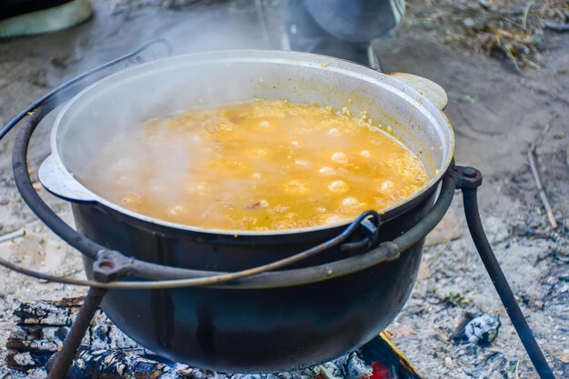 Un delicioso cereal hierve en un caldero al fuego. Picnic de verano en el bosque.