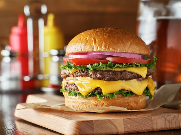 Delicioso cheeseburger duplo em uma tábua de madeira