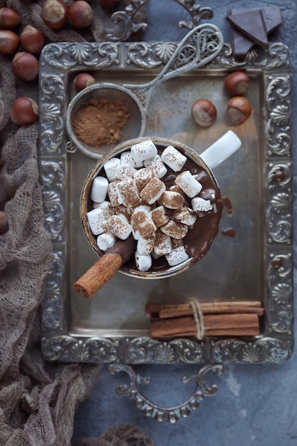 Delicioso chocolate caliente navideño con malvaviscos, nueces y canela en una bandeja de plata