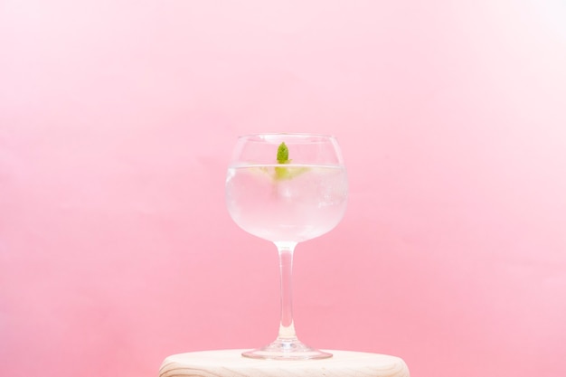 Foto delicioso cóctel gin tonic decorado con rollo de canela fresa y menta sobre un fondo rosa