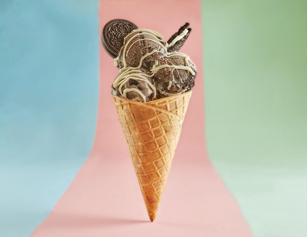 Delicioso cone de sorvete de chocolate com chocolate branco em fundo rosa e azul