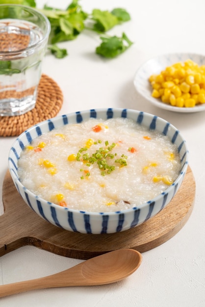 Delicioso congee de gachas de arroz con grano de maíz y verduras sobre fondo blanco de mesa